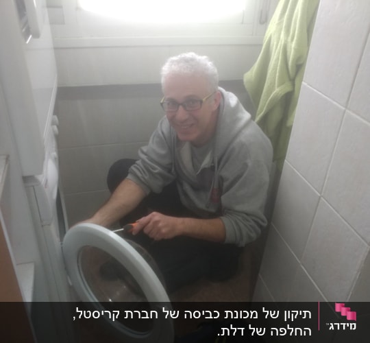 אדם מתקן מכונת כביסה עם מברג